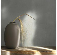 Dekorative Tapete mit Textilmuster und Vase mit Getreideähre auf einem Holztisch.