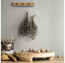 Dekorative Szene mit Holzelementen, Kräutern und Nüssen vor einer strukturierten Wand
