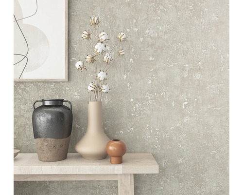 Nahaufnahme eines dekorierten Tisches mit Vasen, Baumwollzweigen und einem Kunstwerk an einer strukturierten Wand