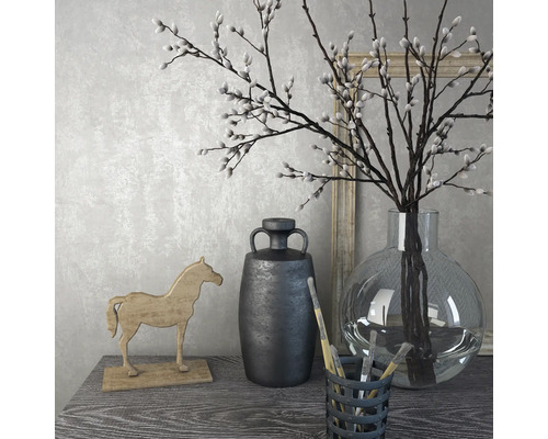 Dekoratives Stillleben mit Vase, Zweigen, Holzpferd und Krug auf einem Tisch.