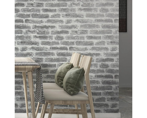 Innenraum mit einer Wandtapete in Steinoptik, Stühlen und Tisch.