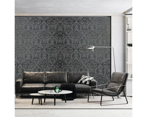 Wohnzimmer mit grauer, gemusterter Tapete, Sofa, Sessel und Couchtischen