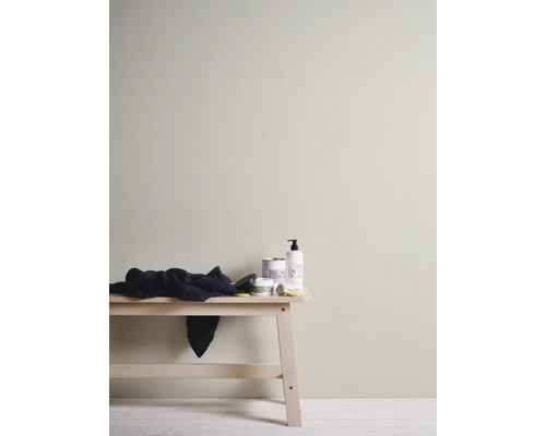 Helle Einrichtungsszene mit Holzbank, Handtuch und verschiedenen Badezimmerartikeln.