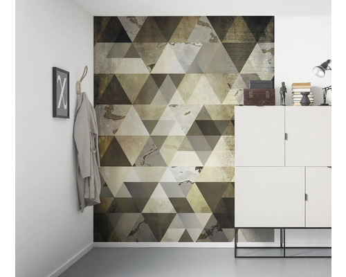Raumszene mit einer Wandtapete mit geometrischem Dreiecksdesign, einem weißen Schrank und dekorativen Elementen.