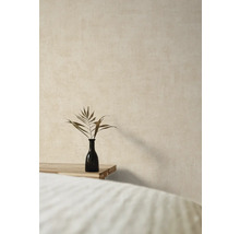 Dekorative Vase mit Pflanzenzweig auf einem Holztisch vor einer strukturierten Wand.