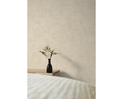 Dekorative Vase mit Pflanzenzweig auf einem Holztisch vor einer strukturierten Wand.