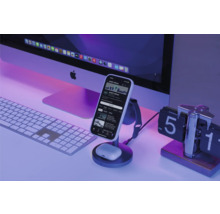 Schreibtischszene mit Smartphone auf Ladestation, Computermonitor, Tastatur und Uhr