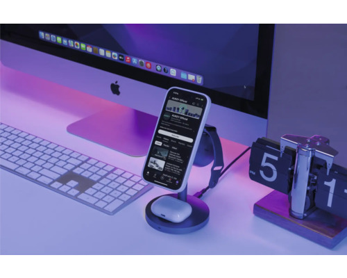 Schreibtischszene mit Smartphone auf Ladestation, Computermonitor, Tastatur und Uhr