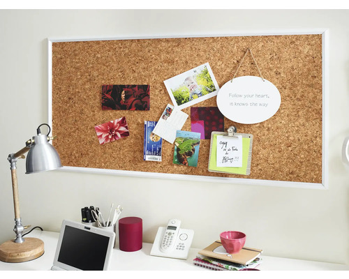 Arbeitsplatz mit Korkwand, Fotos, Notizen und Büromaterialien.
