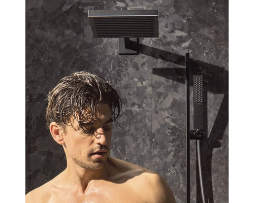 Mann unter einer quadratischen Duscharmatur mit Handbrause