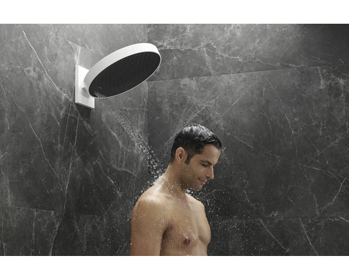 Mann duscht unter einer runden Kopfbrause im Badezimmer.