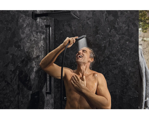 Mann unter der Dusche mit Kopfbrause und Handbrause im Badezimmer