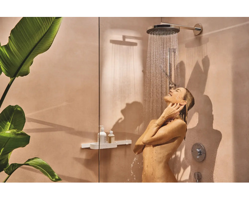 Frau unter einer Regendusche im Badezimmer mit Duschregal und Zimmerpflanze