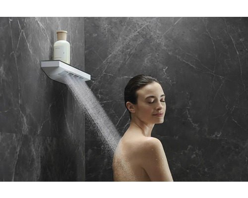 Frau unter einer Kopfbrause mit Wasserstrahl in einem Badezimmer mit Marmorwand