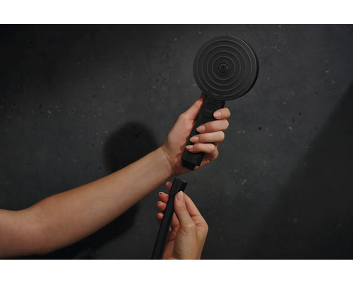 Eine Handbrause mit Schlauch wird von zwei Händen gehalten.