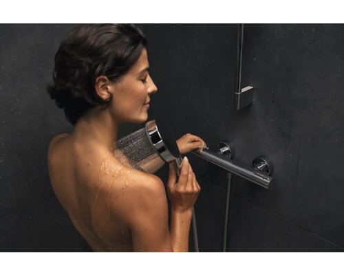 Frau unter der Dusche mit Handbrause und Thermostatarmatur