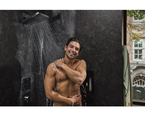 Mann unter einer Regendusche im Badezimmer