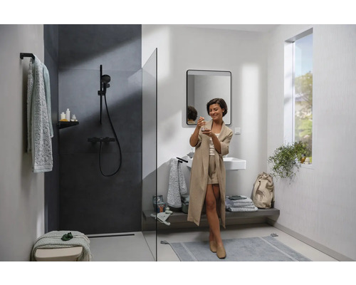 Helles Badezimmer mit Dusche, Waschbecken und einer Frau