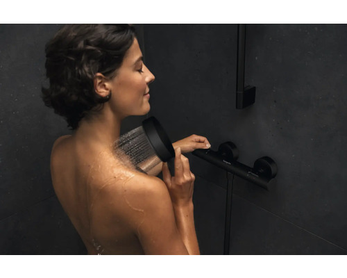 Frau unter der Dusche mit Handbrause und Thermostatarmatur