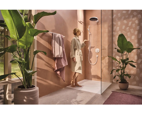 Helles Badezimmer mit ebenerdiger Dusche, Handtüchern und Zimmerpflanzen für ein modernes Ambiente.