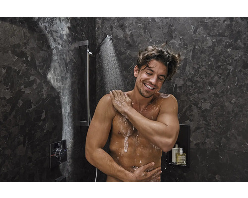 Mann unter einer Dusche mit dunklen Marmorwänden