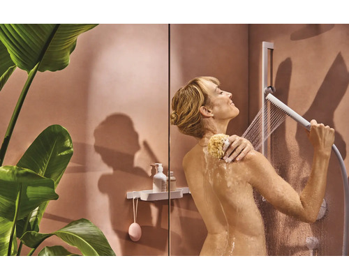 Frau benutzt Handbrause und Badeschwamm in der Dusche.
