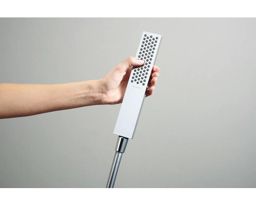 Eine Hand hält einen rechteckigen Duschkopf der Marke Hansgrohe