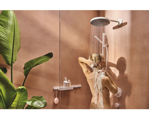 Frau duscht unter einer Duschgarnitur im Badezimmer mit Pflanzen