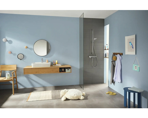Helles Badezimmer mit Waschtisch, Spiegel, Dusche und Accessoires.