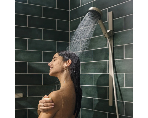 Frau unter der Dusche mit Handbrause in einem Badezimmer mit Fliesen