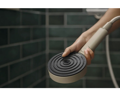 Handbrause in der Hand vor gefliestem Hintergrund