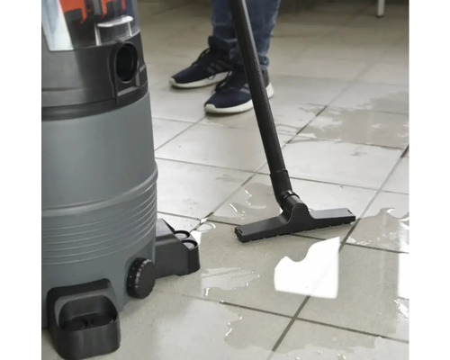 Ein Nass Trockensauger wird auf einem gefliesten Boden verwendet, um stehendes Wasser aufzusaugen.