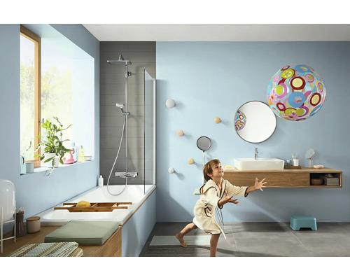 Helles Badezimmer mit Badewanne, Dusche, Waschtisch und spielendem Kind