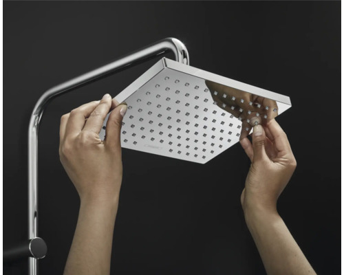 Quadratischer Duschkopf an Duschstange mit Händen, die Düsen reinigen