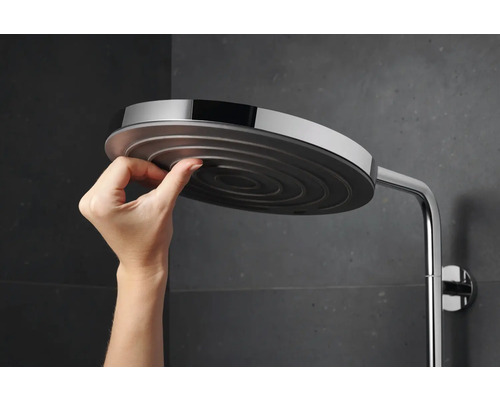 Hand justiert einen runden Duschkopf an einer Duschstange.