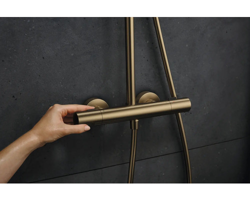 Frauenhand bedient Duscharmatur in Goldoptik