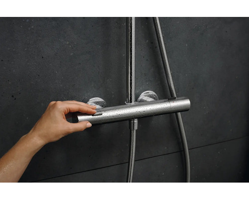 Duscharmatur mit Hand am Temperaturregler im Badezimmer