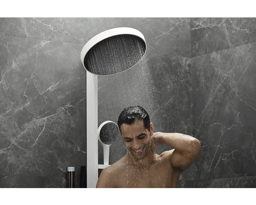 Mann unter einer Kopfbrause mit Handbrause im Badezimmer