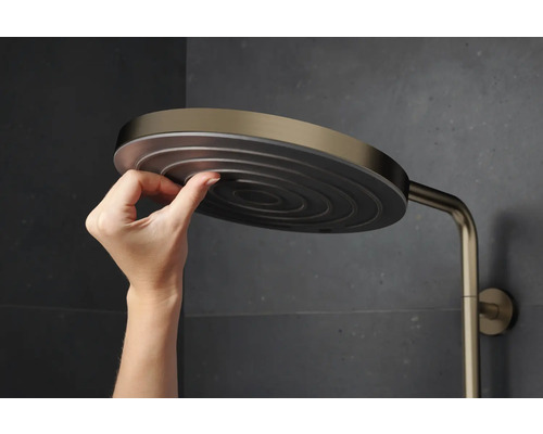 Eine Hand, die einen Duschkopf hält, der an einer Duschstange befestigt ist.