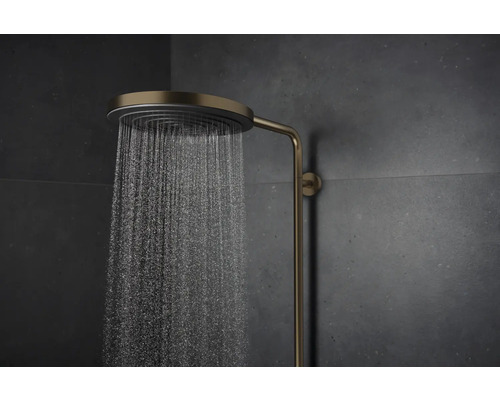 Messingfarbene Regendusche mit Wasserstrahl vor dunkler Wand