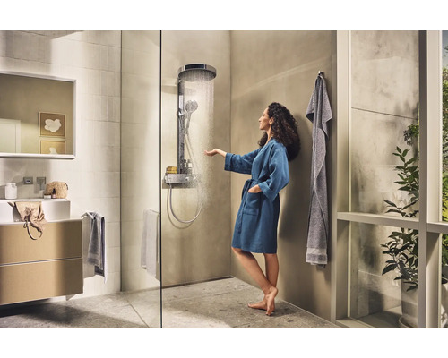 Helles Badezimmer mit Dusche, Waschbecken und einer Frau im Bademantel, die das Wasser berührt