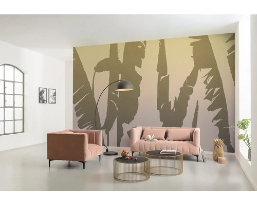 Wohnzimmer mit rosa Sofa, Sessel, Couchtischen, Bogenlampe und Fototapete mit Pflanzenmotiven