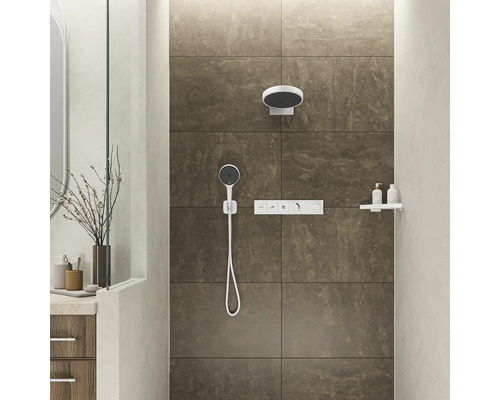 Duschbereich mit Kopfbrause, Handbrause und Armatur vor gefliester Wand