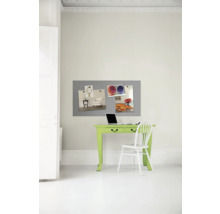 Arbeitszimmer mit grünem Schreibtisch, weißem Stuhl, Laptop und grauer Magnettafel an der Wand