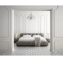 Schlafzimmer mit Bett, Nachttischen, Lampe, Kronleuchter und gemustertem Boden