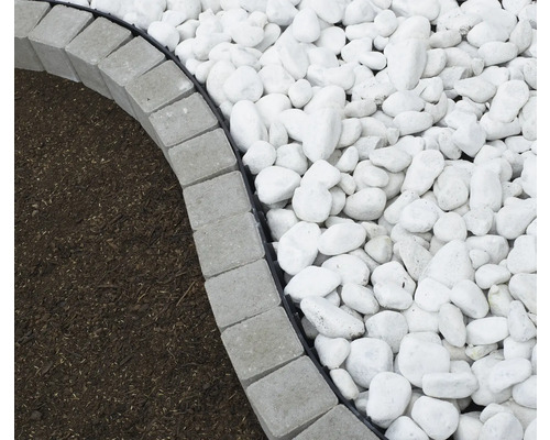 Detailaufnahme von grauen Rasenkantensteinen, Mulch und Zierkies im Garten.