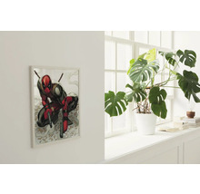 Wohnraum mit einem gerahmten Bild der Comicfigur Deadpool und einer Zimmerpflanze in einem weißen Topf auf einem Fensterbrett.