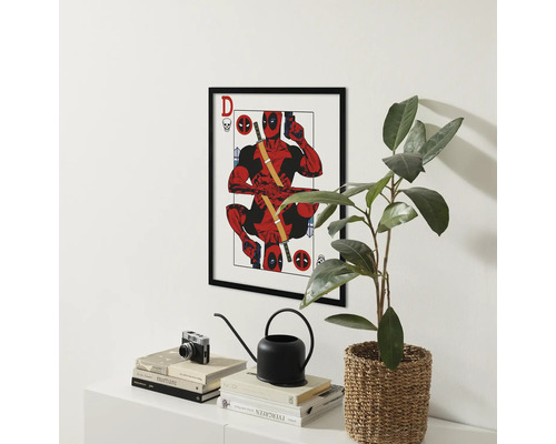 Gerahmtes Deadpool Poster über einem Tisch mit Dekorationen und einer Zimmerpflanze