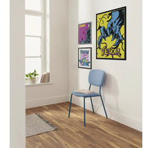 Raumansicht mit drei gerahmten Venom-Postern an der Wand und einem hellblauen Stuhl