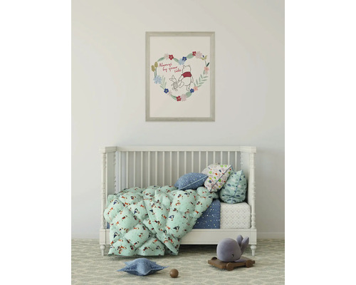 Kinderzimmer mit Gitterbett, Decken und Kissen sowie einem Winnie Puh Bild an der Wand